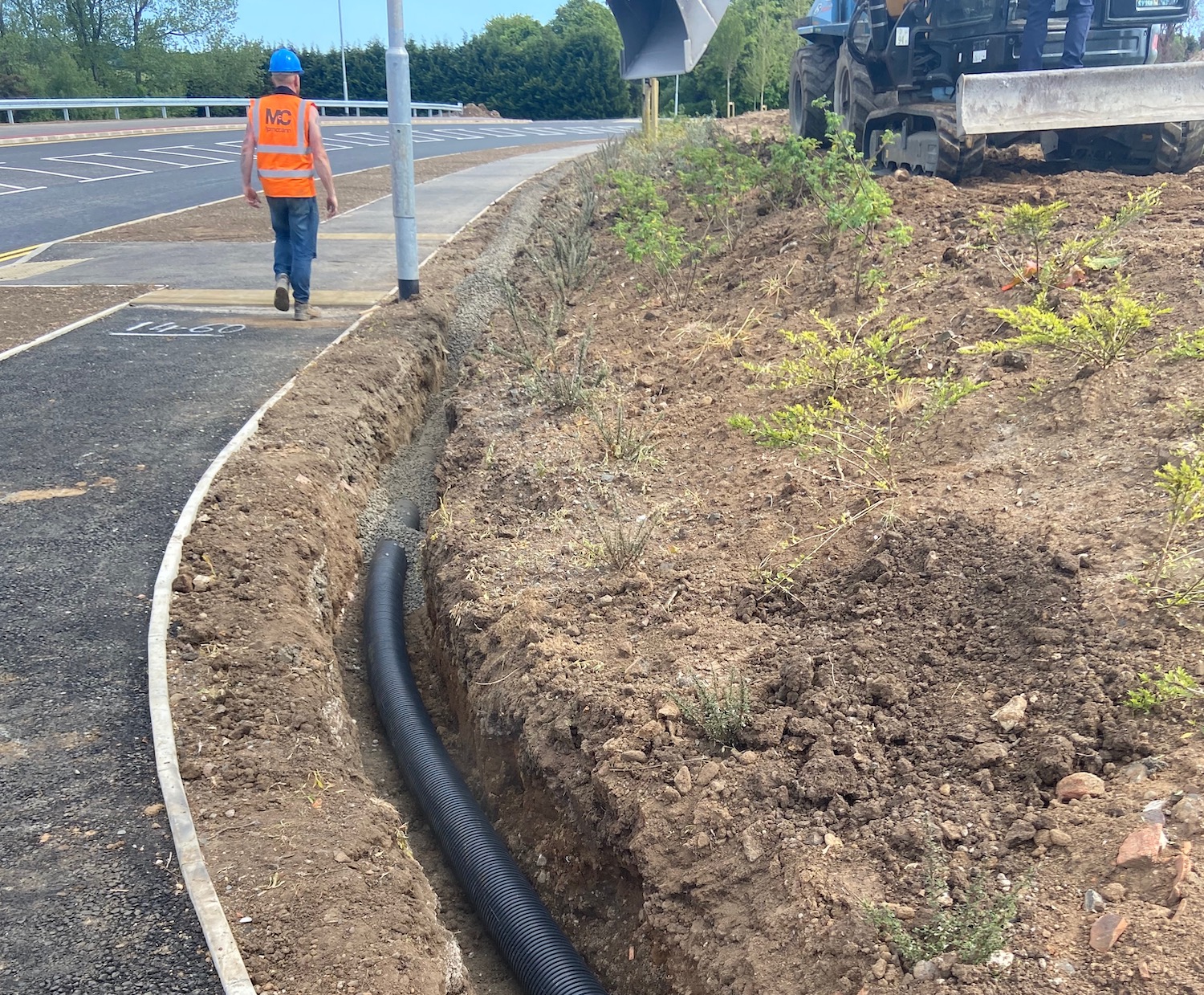 Long
                          ditch with black plastic pipe in it and gravel
                          being placed on top