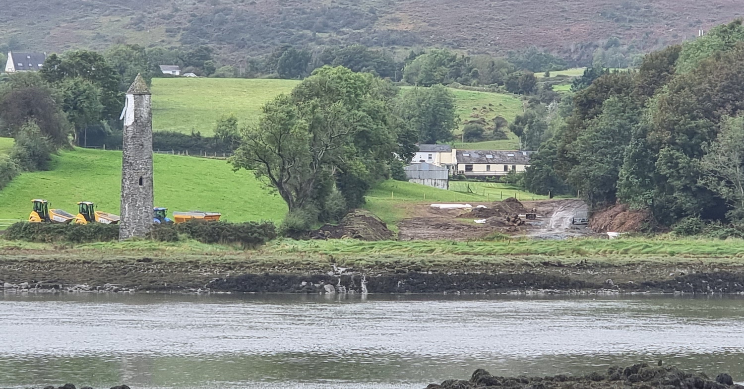 Water in foreground, round tower to left
with various pieces of machinery sitting to
its right.