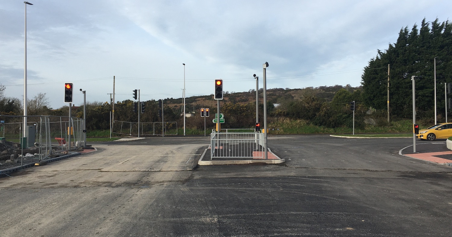 View from the centre of a road towards a
T-junction with a dual-carriageway about 100
metres ahead and traffic signals