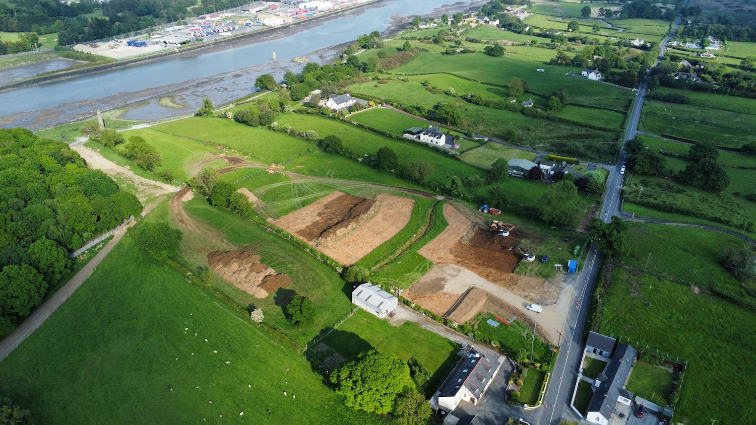 River runs across top left of image. In
the centre is a field that has been turned
over and flattened, with piles of earth to one
side.
