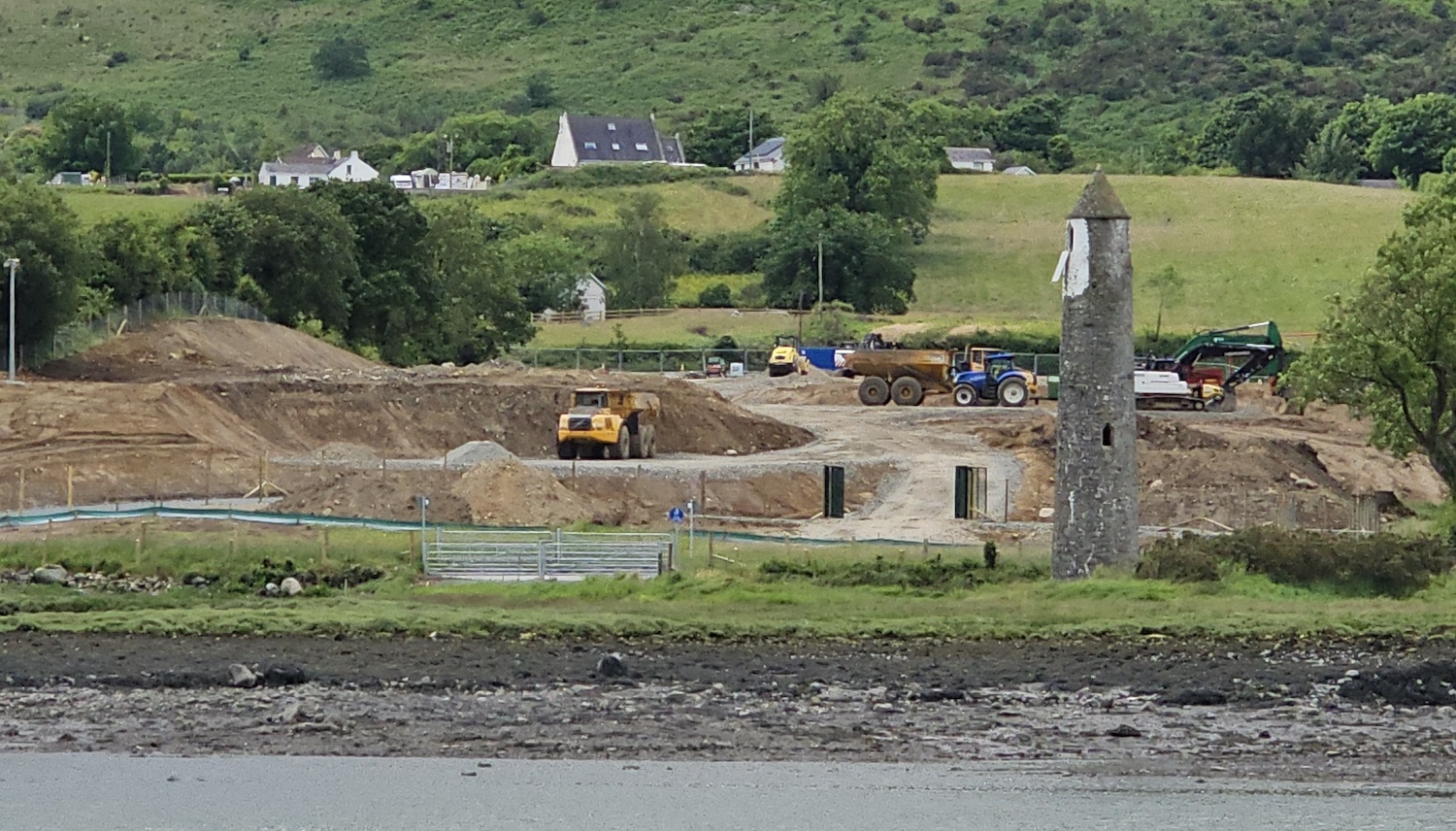 Looking across a river with Narrow Water
tower on the right and machinery removing
topsoil beside it.