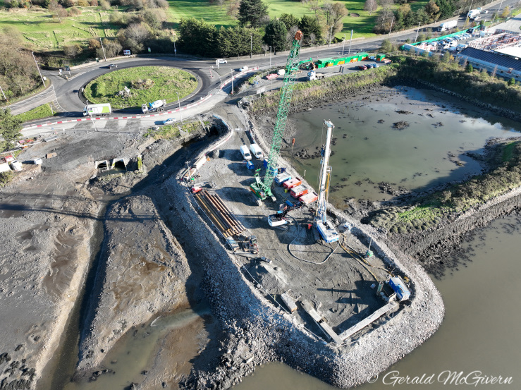 Rock platform partially in water with a
pile driver at the end of it.