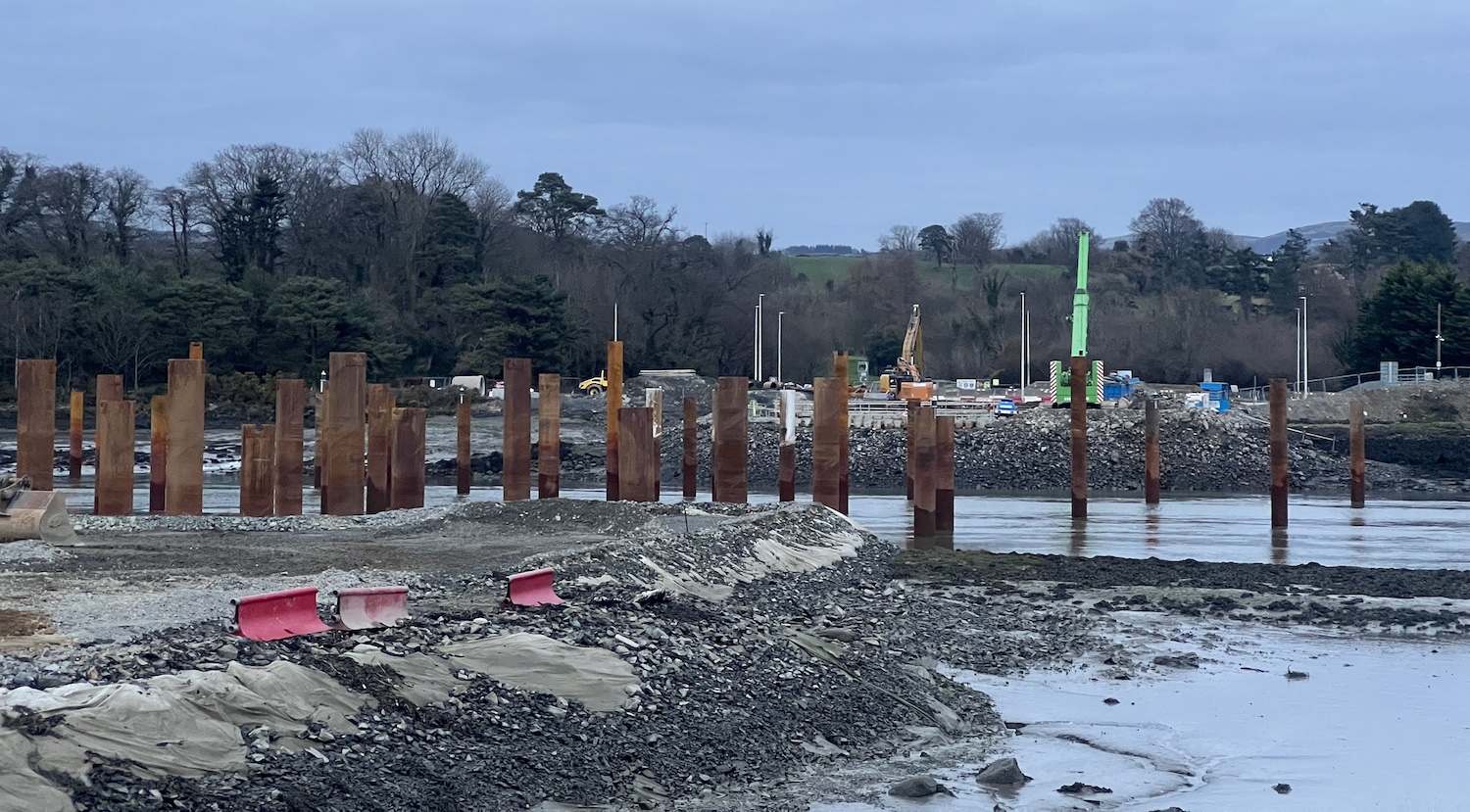 Low water with mud visible and perhaps 20
rust-coloured metal piles sticking out of the
water